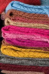 Texture of warm, pastel clothes and knitted scarves on a white background. Winter, autumn clothes.