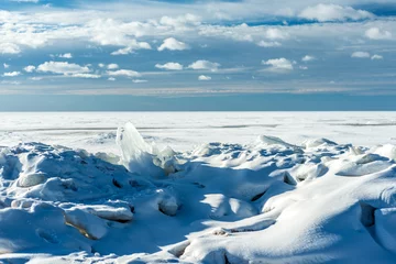 Fotobehang winter landscape of the North sea with cloudy sky and transparent ice floes under the snow © Valerii Ivanov