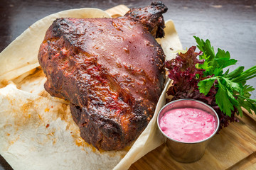 Baked Eisbein with wegetables on wooden board.