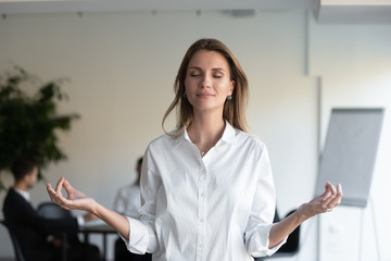 Calm businesswoman meditate relieving negativity at workplace
