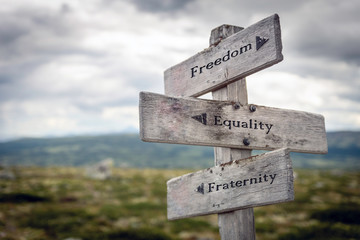 Freedom, equality and fraternity text on wooden sign post outdoors in landscape scenery. Business, quotes and motivational theme concept.