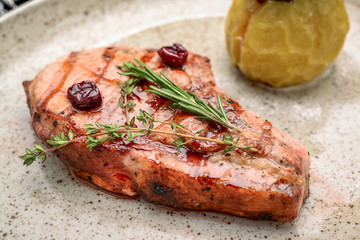 Pork steak on the bone with cherry-ginger sauce with ingredients on messy sackcloth background.
