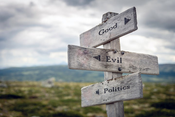 Good, evil and politics text on wooden sign post outdoors in landscape scenery. Business, quotes and motivational theme concept.