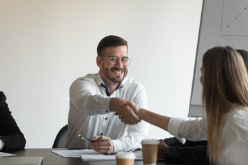 Excited businessman handshake colleague greeting at meeting
