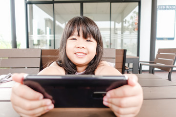 Happy Asian Child girl looking cartoon in smart phone.child, technology and internet concept