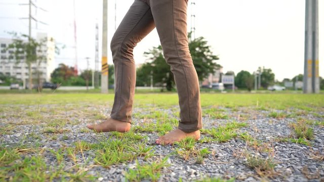man in tactical plant barefoot walking on grasses and stone with white building  high voltage electrical pole on background stock footage