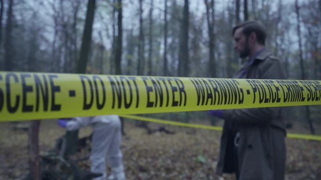 Police detective, forensics team working behind crime scene tape, investigation