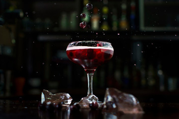 falling berries in a cocktail with splashes on the background of a professional bar