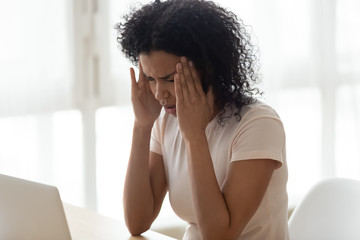 Tired African American woman touching temples, suffering from headache