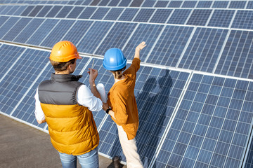 Two engineers or architects examining the construction of a solar power plant, standing with...