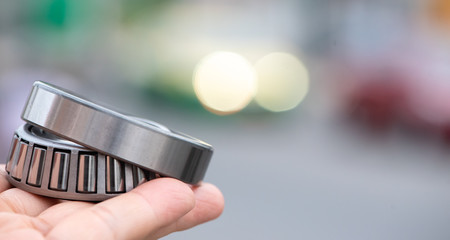 Automotive wheel tapered roller bearing on road background with bokeh