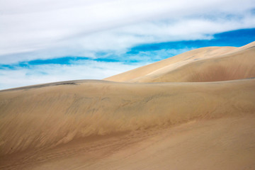 Bright sand dunes under a cloudy sky