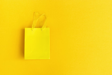 Yellow gift bag on yellow paper background with copy space for your text or congratulations. Summer sale flat lay. Creative colorful greeting card. 