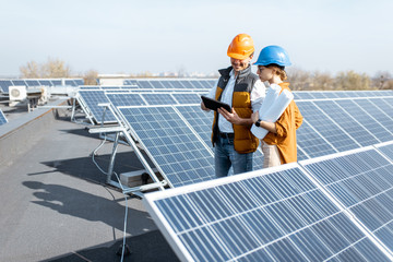 Two engineers or architects examining the construction of a solar power plant, walking with digital...