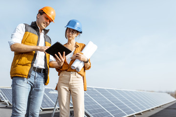 Two engineers or architects examining solar power plant with a digital tablet. Solar station...