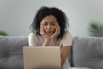 Lazy bored African American woman using laptop, doing routine work