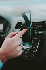 A man holds a smartphone with a layout in the car on the background of clouds