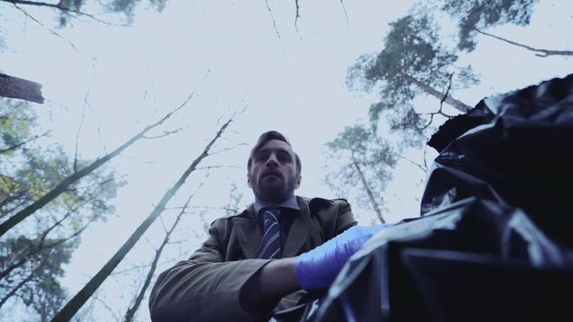 Comic detective looking into body bag, funny grimace on face, awkward crime