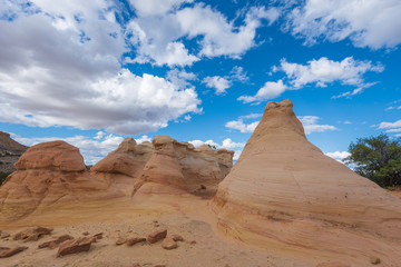 Fototapeta na wymiar Landscape of yellow striped conical rock formations and clouds at Ojito Wilderness in New Mexico