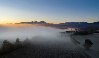 Beautiful foggy autumn morning in Bavaria - aerial view of Wilparting Church before Alps in Chiemgau