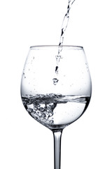 Water is poured into a glass. Splash of water in a wine glass on a white background with bubbles. Studio shot. Water is the basis of life. The concept of a healthy lifestyle