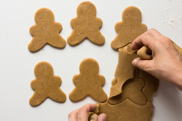 Excess of gingerbread dough removing from rolled out and cutted dough by woman hand on white background