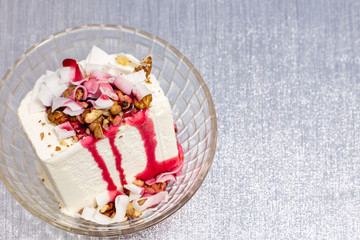 white ice cream with nuts, coconut and topping in a bowl