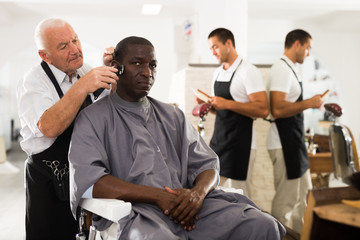 African man getting haircut from elderly barber