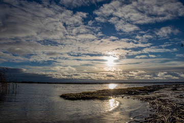 Ice and snow on beach coast with shadows in cold winter evening sunset sky orange sun light