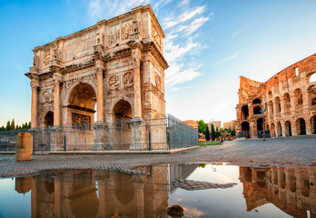 Arch of Constantine and Colosseum in Rome reflection in puddle after rain, Italy. Triumphal arch in...