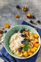 Healthy food for Breakfast, vegetarian and diet food concept. Oatmeal porridge with chia, banana, blueberry, fruits and nuts on a stone countertop with copy space.