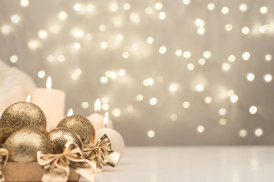 Box with golden christmas ball and candle on gold bokeh background