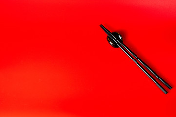 Black chopsticks with holder on red background