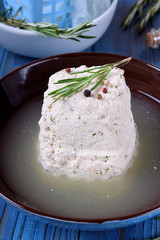 Homemade cheese in the brine on the blue wooden table