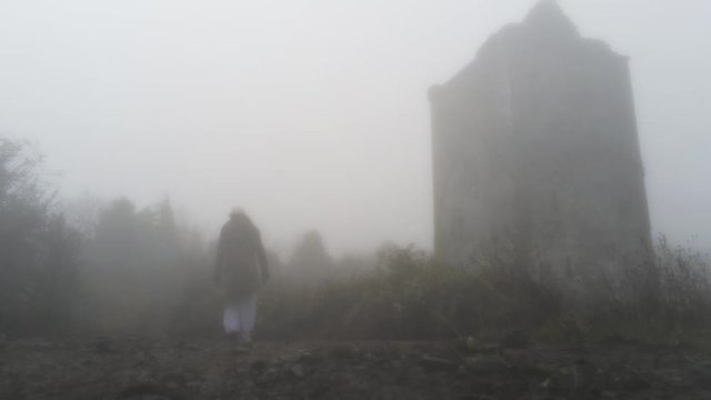 4k Woman walking in front of Merlin Castle in a foggy day, Galway, Ireland