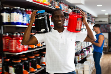 Fine African man with jars of sports supplements