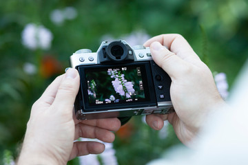 Old-style digital camera (DSLR) in men's hands (close up) with excellent bokeh.