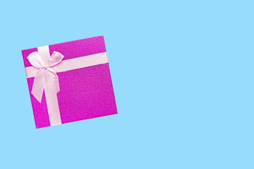 Red gift box with pink ribbon isolated on blue background.