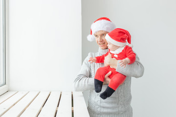 Fatherhood and holidays concept - Father with his baby boy wearing Santa hats celebrating Christmas