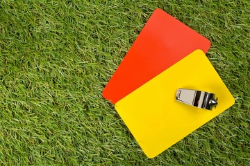 Soccer sports referee yellow and red cards with chrome whistle on grass background flat lay from...