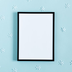 Photo frame and snowflakes on pastel blue background. Christmas, New Year, winter concept. Flat lay, top view, copy space, square
