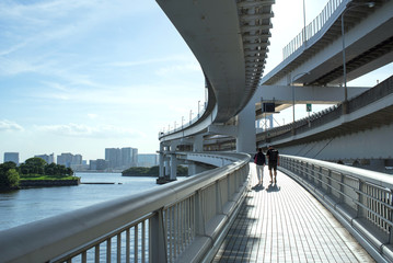 Couple walking across Rainbow Bridge in Tokyo,...