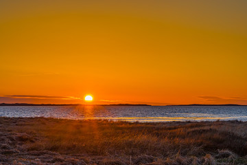 Fototapeta na wymiar Sunset at dusk at the beach along the rocky beach coast.