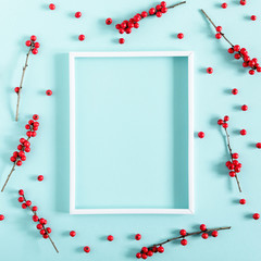 Christmas holiday composition. Photo frame, red berry on pastel blue background. Christmas, New Year, winter concept. Flat lay, top view, copy space, square