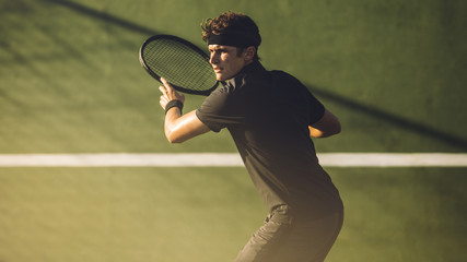 Young player playing tennis on hard court © Jacob Lund