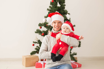 Fototapeta na wymiar Father with his baby boy wearing Santa hats celebrating Christmas.