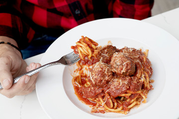Twirled spaghetti on a fork over a bowl of spaghetti and meatballs 
