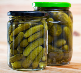 Glass jar with pickled cucumbers on wooden background