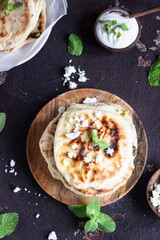 Onion, mint and cheese small flatbreads served on a wooden plate. Gozleme - crispy, golden Turkish flatbreads.