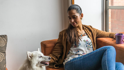 Beautiful latin woman resting while drinking a beverage with her pet